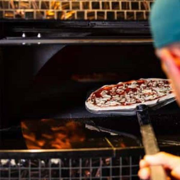 Une pizza enfournée dans le four de la pizzeria