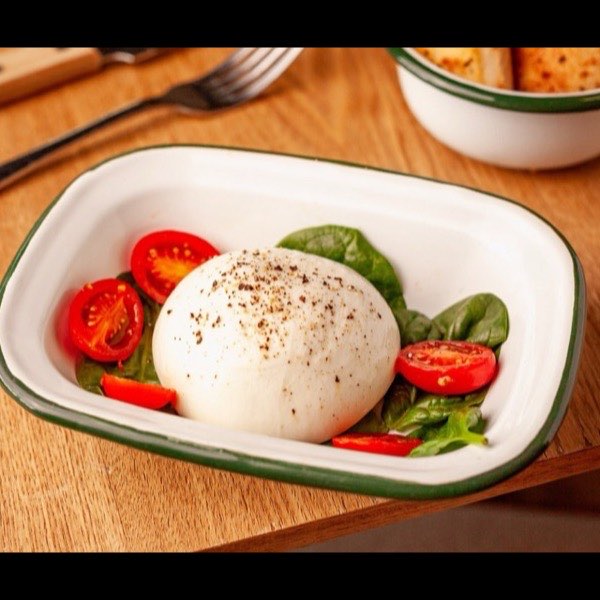 Une burrata servie avec tomates cerises et pousses d'épinards