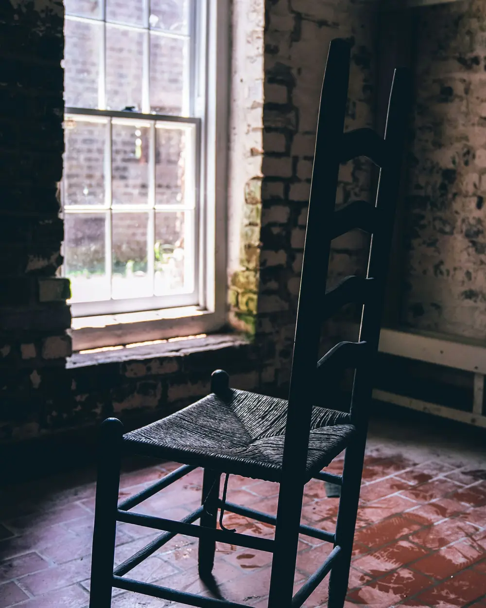 Chaise à dossier à barreaux, assise paillée neuve, près d'une fenêtre