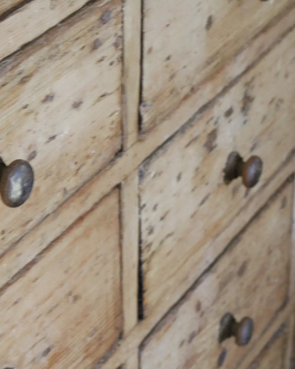 Façade de tiroirs anciens en bois grisé et usé, boutons ternis