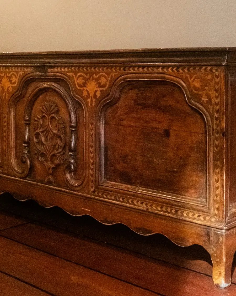 Coffre ancien en chêne sculpté de médaillons, restauré, posé sur un parquet