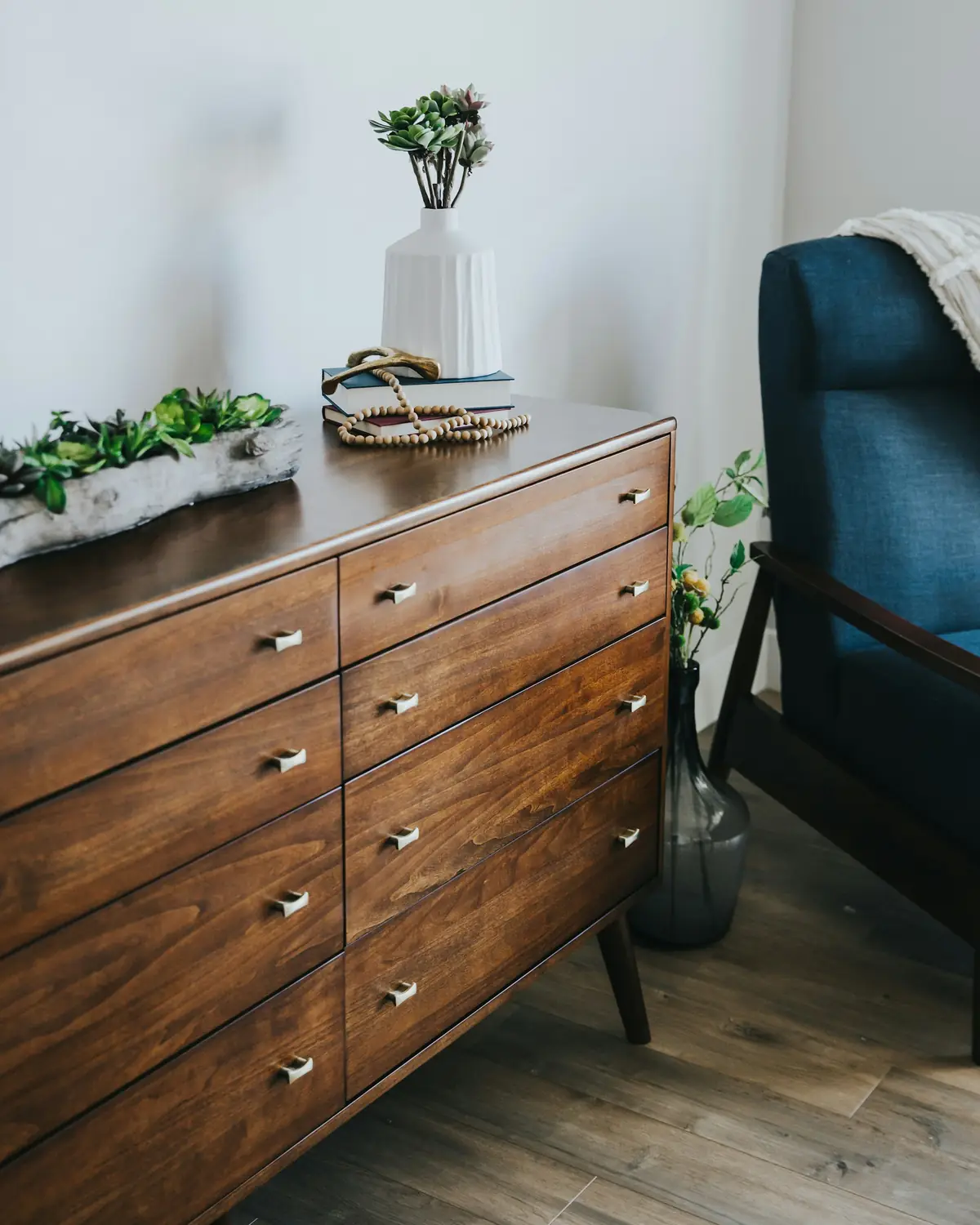 Commode en noyer à huit tiroirs avec des boutons en laiton, posée dans une chambre