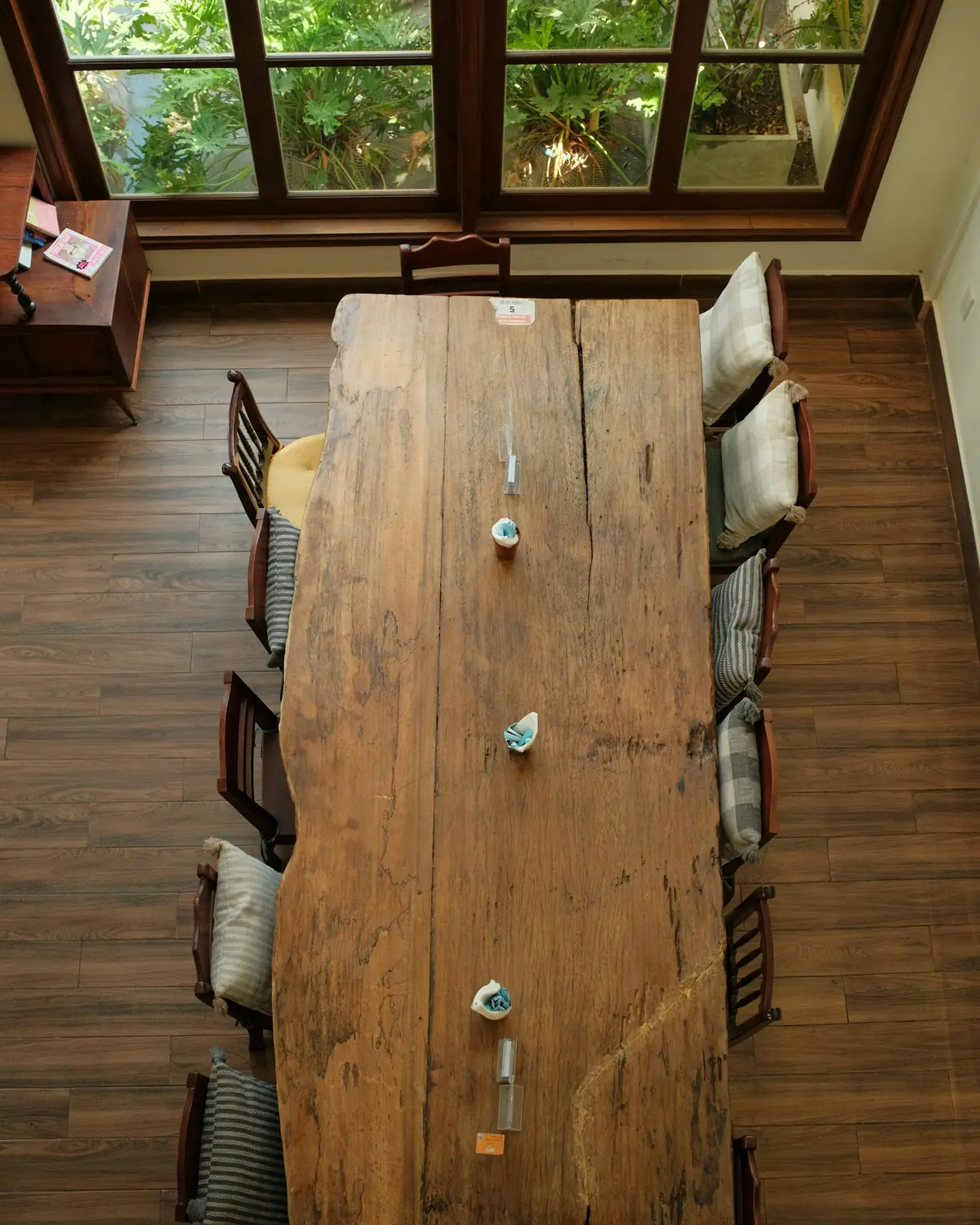 Longue table de ferme en chêne massif vue de dessus, entourée de chaises dépareillées