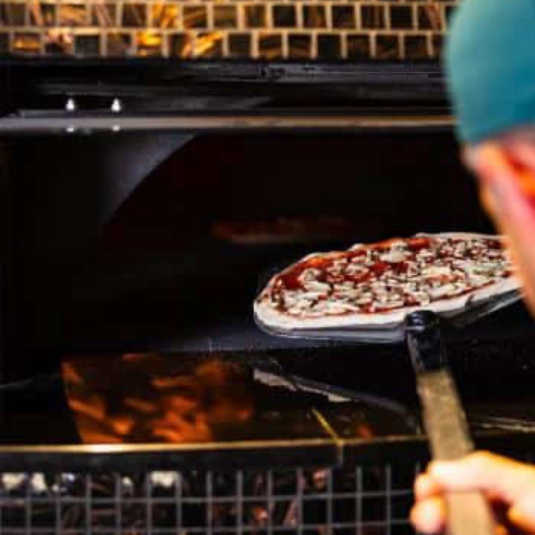 Une pizza enfournée dans le four de la pizzeria